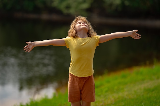 Niño feliz con los brazos levantados disfrutando de la libertad en la naturaleza niño con los brazos abiertos medita niño disfrutando