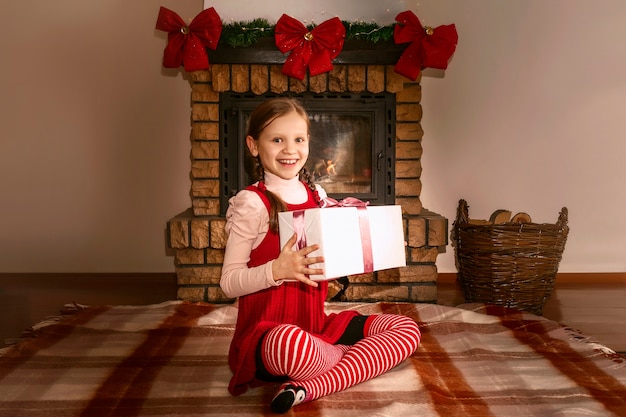 Niño feliz con la caja de regalo en el fondo de la chimenea de Navidad