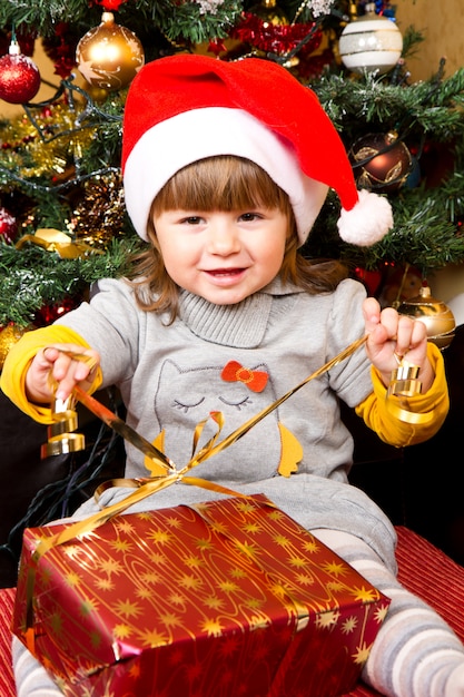 Niño feliz en la caja de regalo de Navidad de apertura de sombrero de Santa