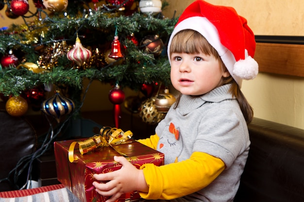 Niño feliz en la caja de regalo de navidad de apertura de sombrero de santa