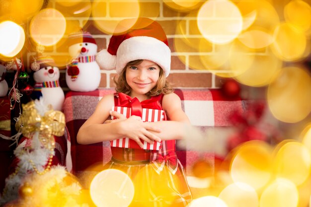 Niño feliz con caja de regalo de Navidad. Niño gracioso jugando en casa