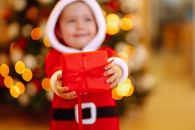 Niño feliz con caja de regalo roja en las luces de fondo.