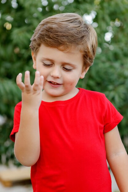 Niño feliz con camiseta roja en el jardín