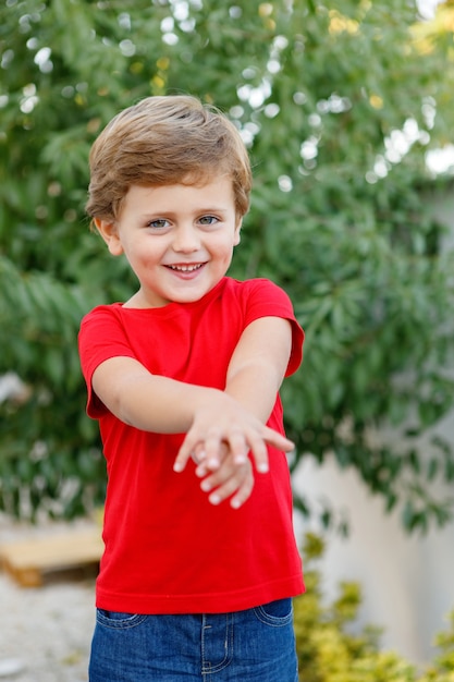 Niño feliz con camiseta roja en el jardín