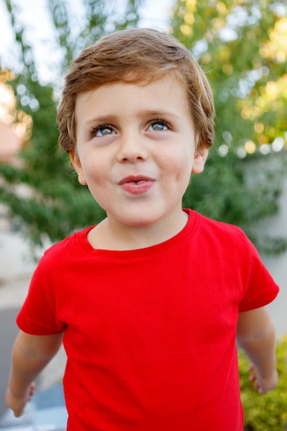 Niño feliz con camiseta roja en el jardín