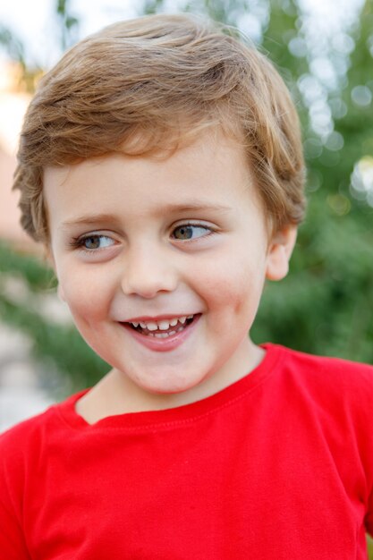 Niño feliz con camiseta roja en el jardín