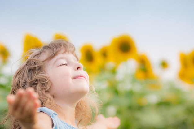 Niño feliz en el campo de girasol de primavera Concepto de libertad