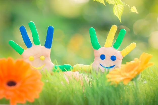 Niño feliz con carita sonriente en las manos contra el fondo verde de la primavera