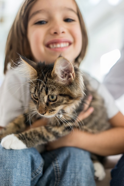 Niño feliz en casa jugando con gatito