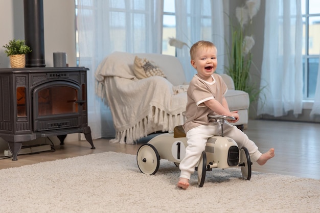 Niño feliz en casa niño pequeño conduciendo un gran coche de juguete vintage y divirtiéndose jugando a un niño sonriente