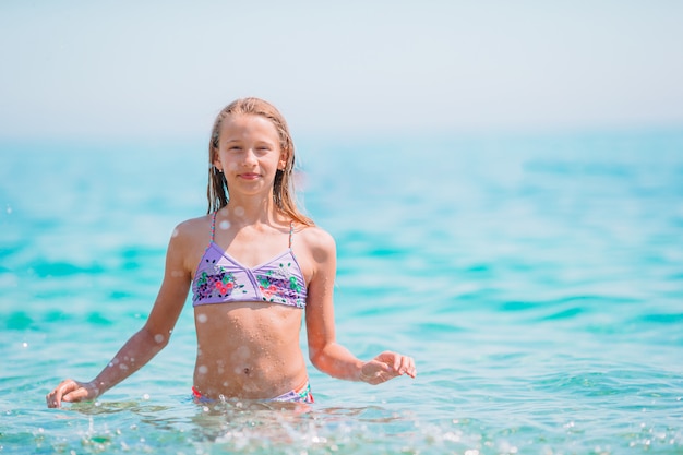 Niño feliz chapoteando en las olas durante las vacaciones de verano