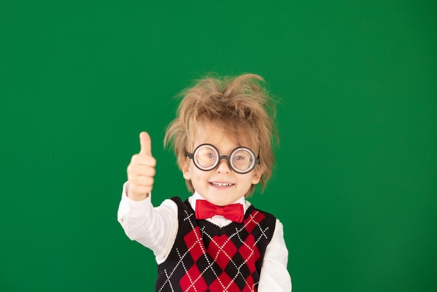 Niño feliz en clase contra pizarra verde