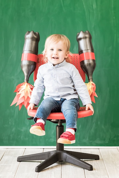 Niño feliz en clase. Niño divertido contra la pizarra. De vuelta a la escuela. Concepto de educación