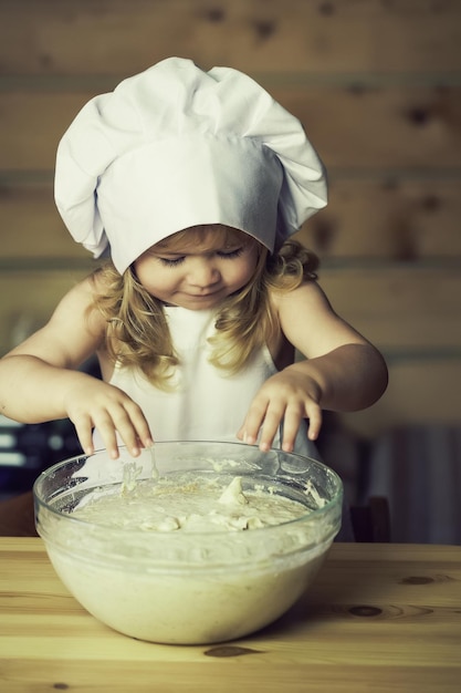 Niño feliz cocinero amasando masa