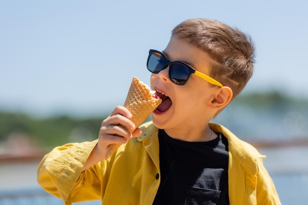 Un niño feliz come helado en un cono de gofre en verano durante un paseo