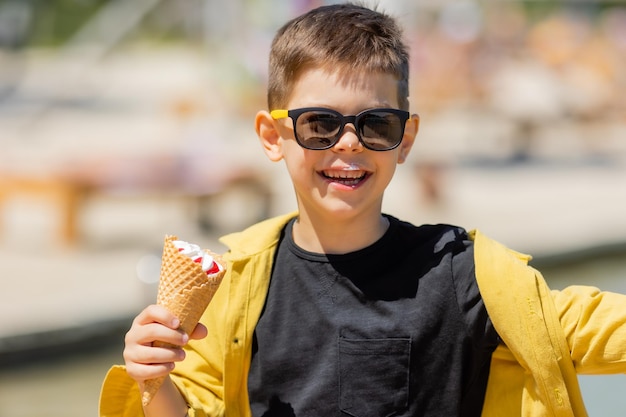 Un niño feliz come helado en un cono de gofre en verano durante un paseo