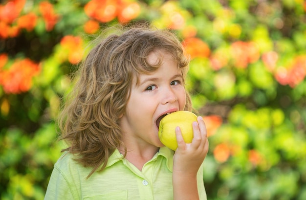 Foto un niño feliz comiendo una manzana verde sonriendo sosteniendo y comiendo un jardín de manzanas frescas