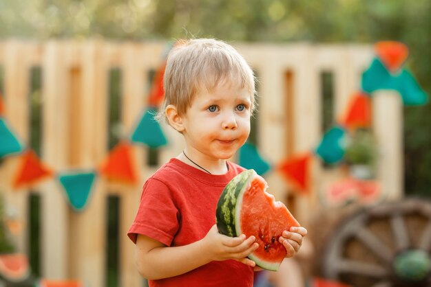 Niño feliz comiendo sandía en la infancia del jardín