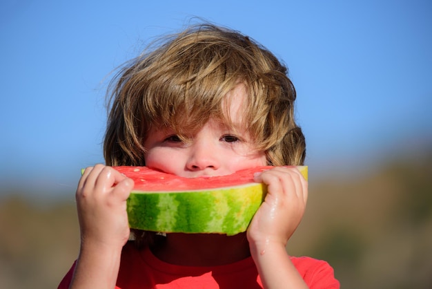 Niño feliz comiendo sandía niño lindo comiendo melón alimentos saludables en el fondo de la naturaleza agua orgánica fresca ...