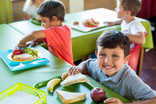 Foto niño feliz con compañeros comiendo