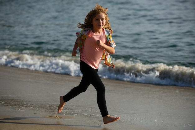 Niño feliz corre hacia el mar Pequeño atleta en entrenamiento Corredor haciendo ejercicio trotar para niños Niño diviértete en la playa junto a la piscina de agua de mar Estilo de vida familiar activo niños deportes acuáticos al aire libre