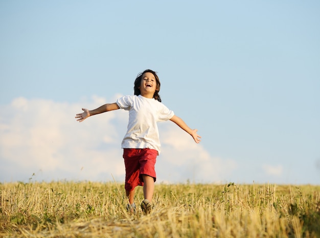 Niño feliz corriendo en el hermoso campo