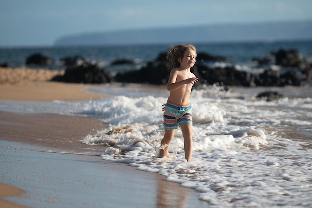 Niño feliz corriendo playa cerca de la orilla del mar niño asombrado emocionado divirtiéndose corriendo por el agua en ...