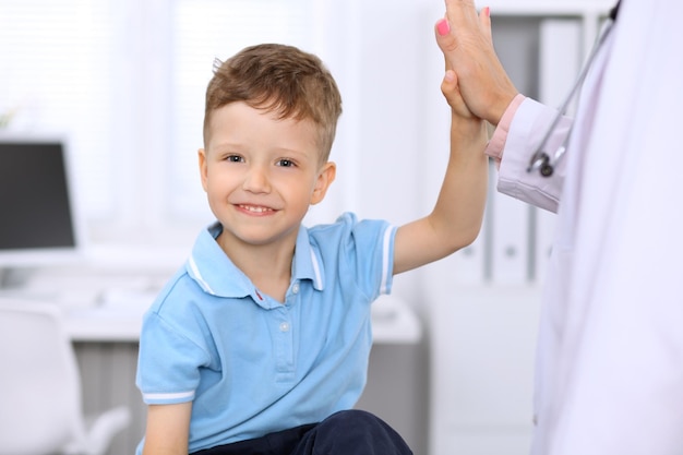 Foto niño feliz dando cinco después de un examen de salud en el consultorio del médico