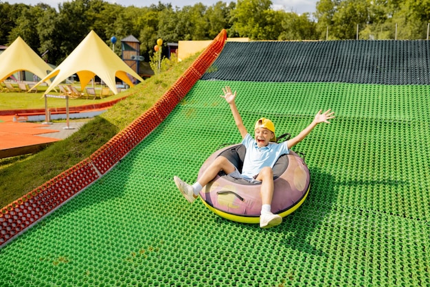 Un niño feliz desciende en un trineo inflable en el parque de diversiones