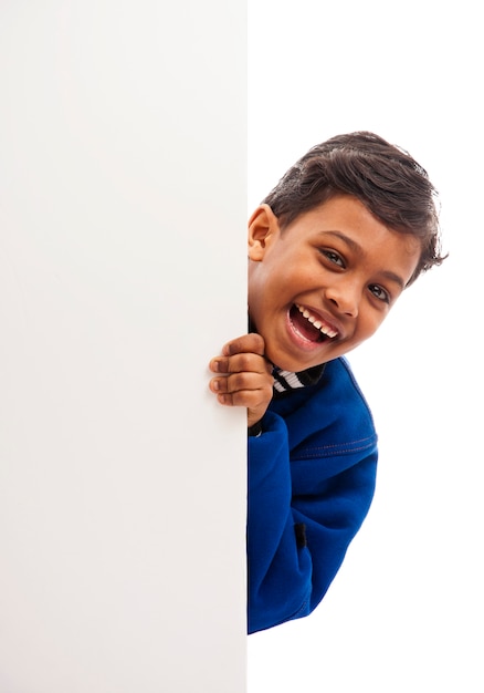 Niño feliz detrás del tablero en blanco