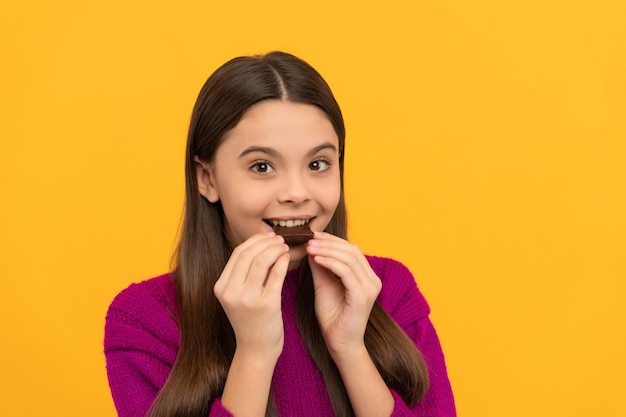 Niño feliz disfruta comiendo delicioso bocadillo de chocolate fondo amarillo delicioso