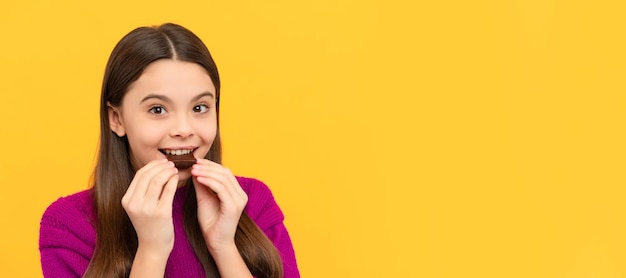 Un niño feliz disfruta comiendo un delicioso refrigerio de chocolate fondo amarillo delicioso Cartel horizontal del espacio de copia de encabezado de banner de cara de niño aislado