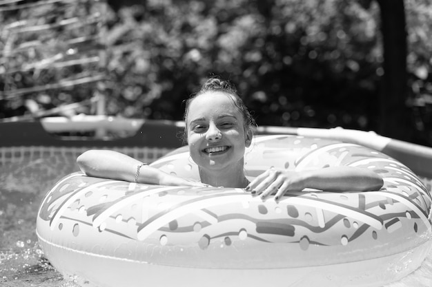 Niño feliz disfruta nadando en el flotador de la piscina de donuts en un día soleado de verano