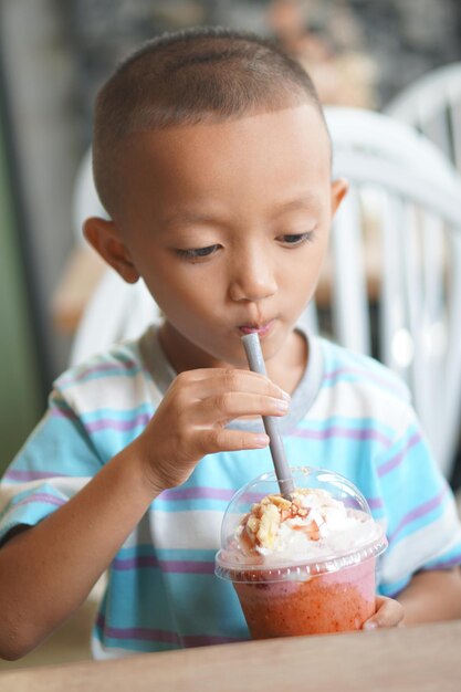 Niño feliz disfrutando de batidos de frutas frescas