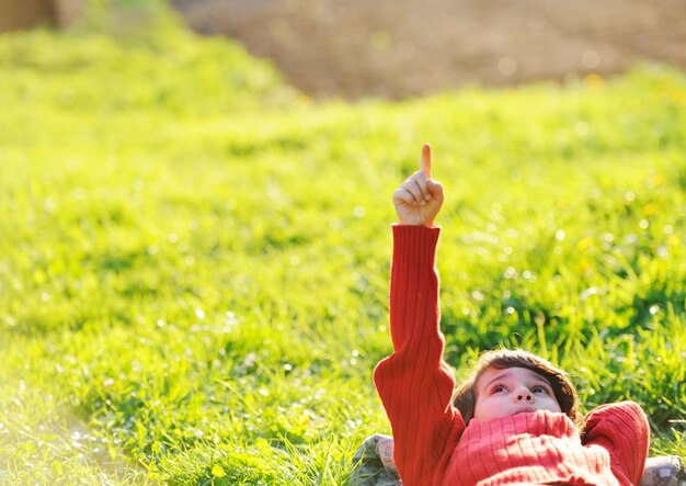 Niño feliz disfrutando soleado verano y día de otoño en la naturaleza en la hierba verde