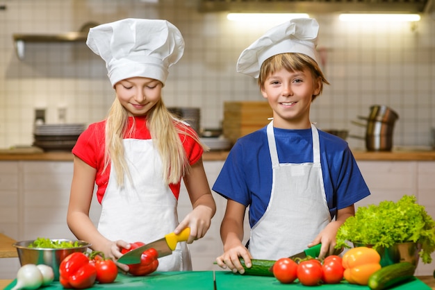 Niño feliz divertido y niña cocinando en la cocina del restaurante