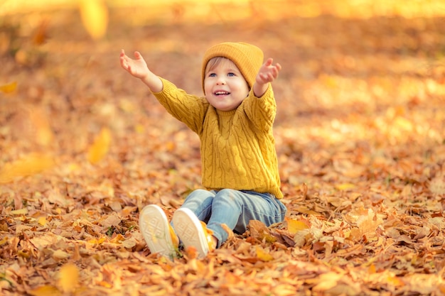 Niño feliz divirtiéndose al aire libre. Niño sonriente jugando en el parque otoño