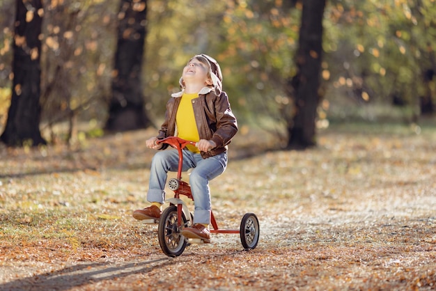 Niño feliz divirtiéndose al aire libre en el parque otoño