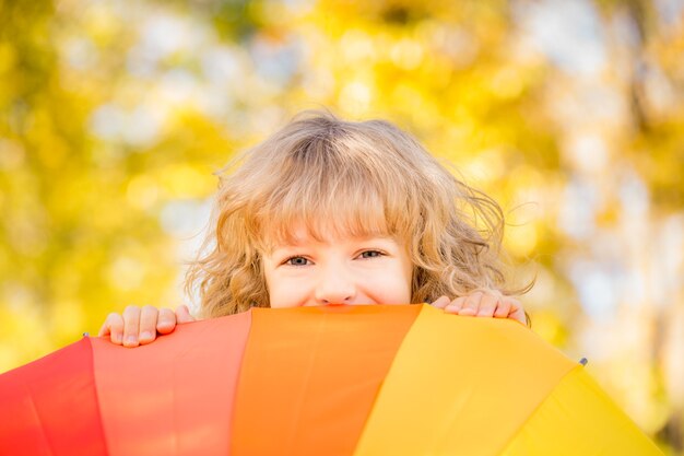 Niño feliz divirtiéndose al aire libre en el parque otoño