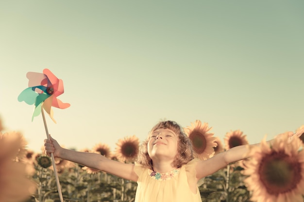 Niño feliz divirtiéndose en el campo de primavera contra el fondo del cielo azul Concepto de libertad