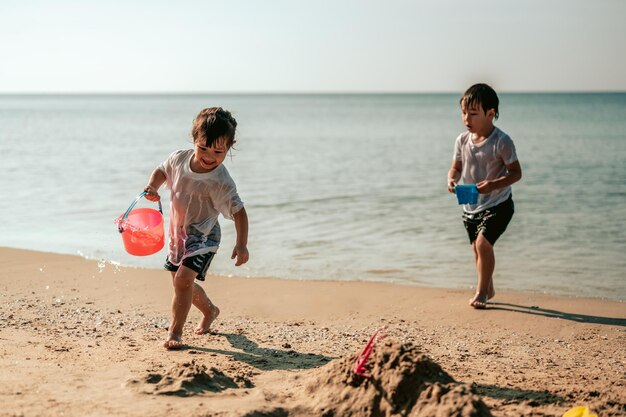 Niño feliz divirtiéndose jugando a la arena en las vacaciones de verano en la playaConcepto de viaje y vacaciones