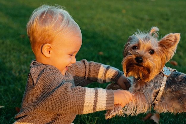 Niño feliz divirtiéndose jugando con un cachorrito en el parque de otoño niño sonriente con rubia