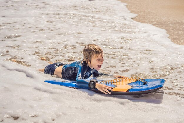 Niño feliz divirtiéndose en la playa de vacaciones con Boogie board