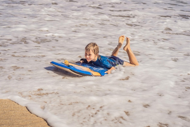 Niño feliz divirtiéndose en la playa de vacaciones con Boogie board