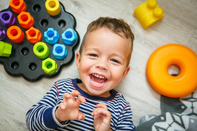 Niño feliz divirtiéndose riendo en el piso - vista superior