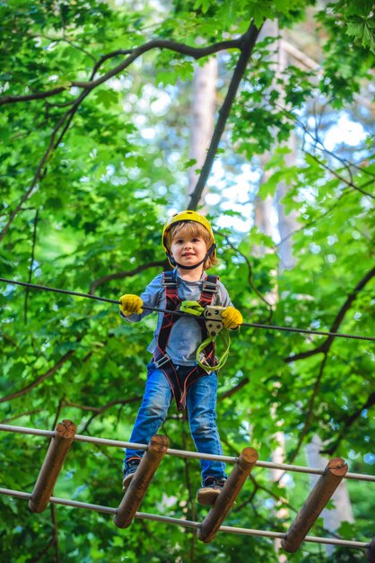 Niño feliz escalando un árbol aventura de desarrollo de la primera infancia escalando parque de alambre alto chi