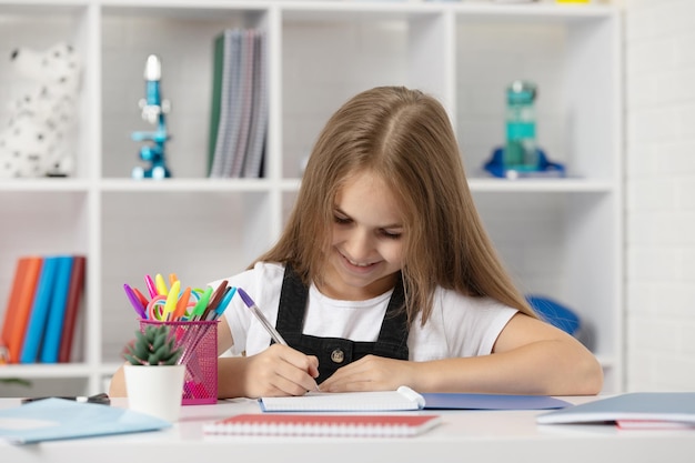 Niño feliz escribiendo en cuaderno en la lección de la escuela en el aula usar uniforme de regreso a la escuela