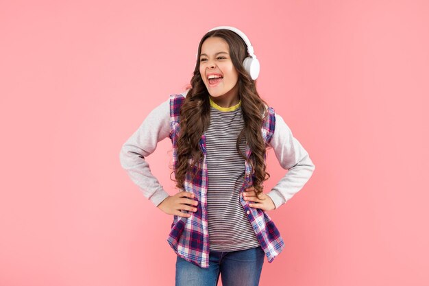 Niño feliz escuchando música en auriculares en la infancia de fondo rosa