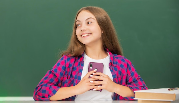 Niño feliz en la escuela hablando por teléfono en el mensaje de fondo de la pizarra