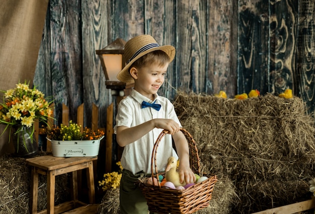 Niño feliz está parado y sostiene una canasta de huevos coloridos. Búsqueda de huevos